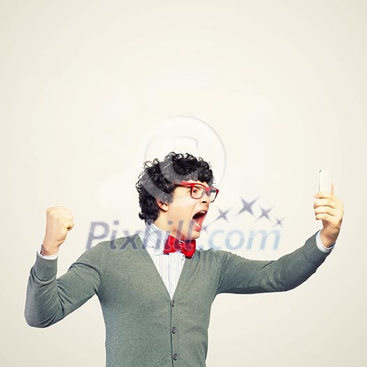 Young businessman with a red tie shouting furiously at his mobile phone Young businessman with a red tie shouting furiously at his mobile phone