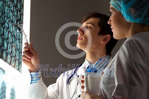Image of two young two doctors discussing x-ray results Image of two young two doctors discussing x-ray results