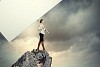 Image of business woman standing atop of hill holding blank banner