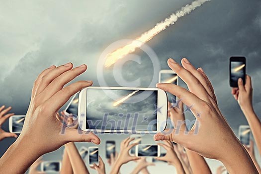 Close up of human hands taking photo of falling meteorite Close up of human hands taking photo of falling meteorite
