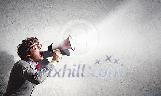 Portrait of young man shouting loudly using megaphone