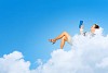 Image of businesswoman lying on clouds with book