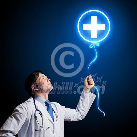 Young male doctor holding balloon with medical sign