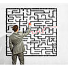 Back view image of young businessman trying to find way out of maze