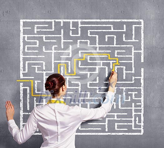 Back view image of young businesswoman trying to find way in labyrinth Back view image of young businesswoman trying to find way in labyrinth