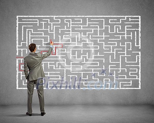 Back view image of young businessman trying to find way out of maze Back view image of young businessman trying to find way out of maze
