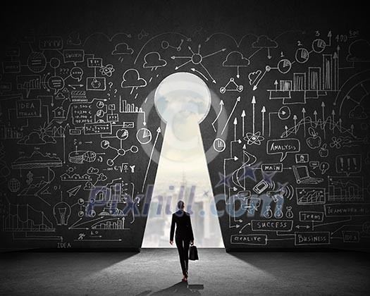 Silhouette of businesswoman against black wall with key hole