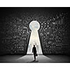 Silhouette of businesswoman against black wall with key hole