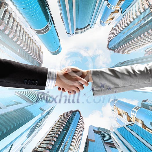 Close up image of hand shake against skyscrapers