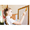 Little cute girl with paint brush and easel