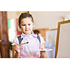 Little cute girl with paint brush and easel
