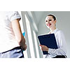 Image of young businesswoman holding folder and talking to colleague