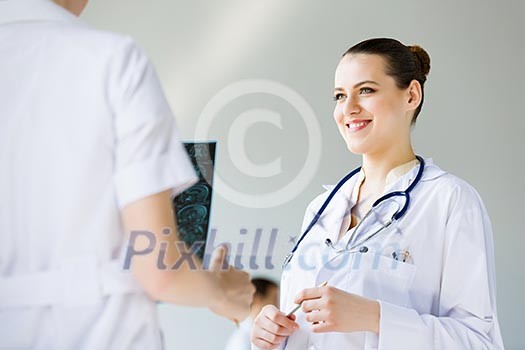Attractive young female doctor examining x-ray results Attractive young female doctor examining x-ray results