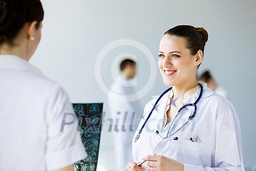 Attractive young female doctor examining x-ray results Attractive young female doctor examining x-ray results
