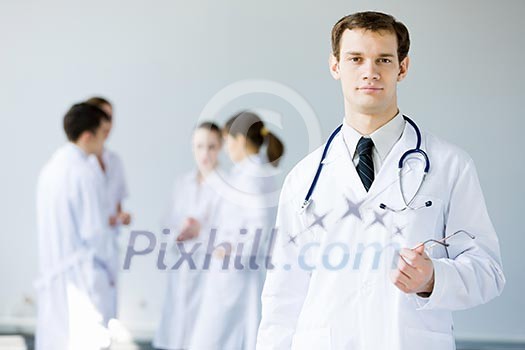 Young doctor in uniform and colleagues at background