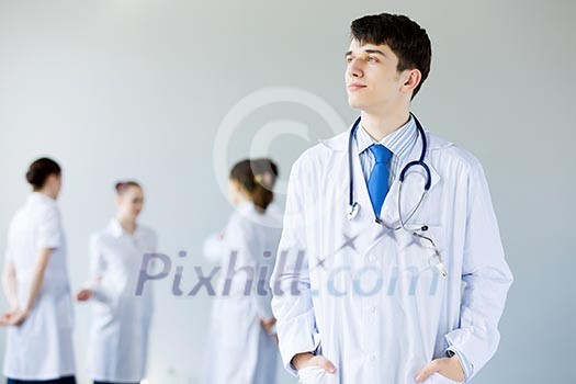 Young doctor in uniform and colleagues at background Young doctor in uniform and colleagues at background
