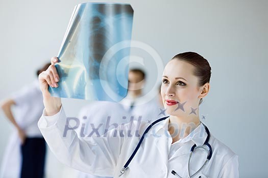 Attractive young female doctor examining x-ray results
