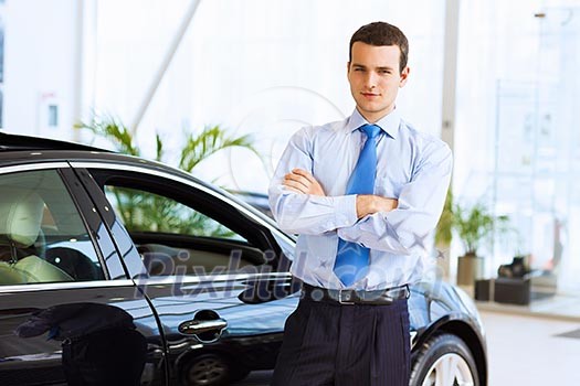 Image of handsome young businessman in suit standing near car Image of handsome young businessman in suit standing near car