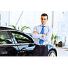 Image of handsome young businessman in suit standing near car