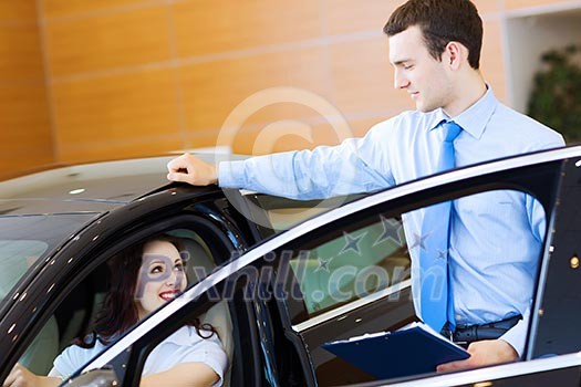 Attractive woman at car salon with consultant choosing a car