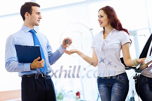 Attractive woman at car salon with consultant choosing a car