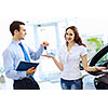 Attractive woman at car salon with consultant choosing a car