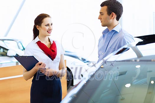 Young man choosing car at salon with help of consultant Young man choosing car at salon with help of consultant
