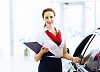 Young attractive woman consultant of car center standing near car