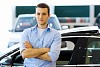 Handsome young man consultant at car salon standing near car