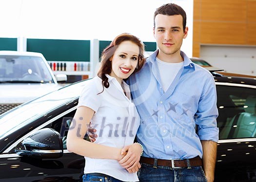Two pretty young people smiling standing near car Two pretty young people smiling standing near car