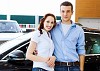 Two pretty young people smiling standing near car