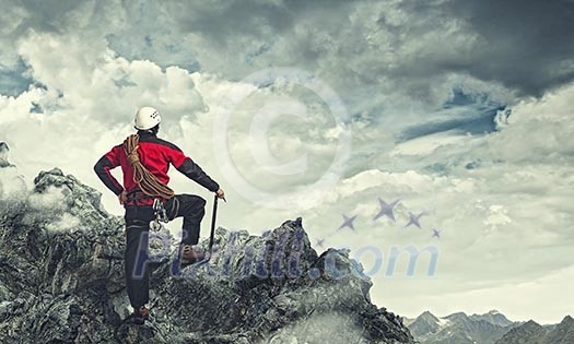 Image of young man mountaineer standing atop of rock Image of young man mountaineer standing atop of rock