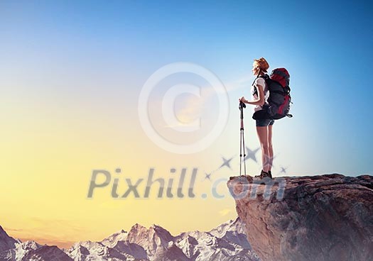 Pretty young woman tourist standing on top of mountain