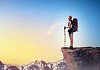 Pretty young woman tourist standing on top of mountain