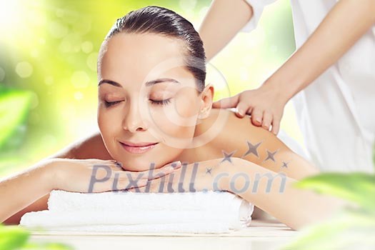 Young pretty woman with clear skin at spa salon getting massage