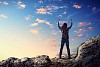 Image of young man mountaineer standing atop of rock