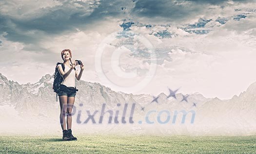 Pretty young woman tourist standing on top of mountain