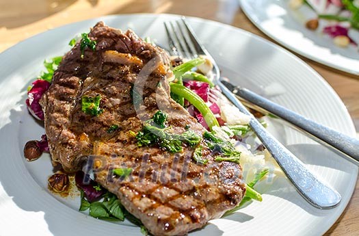 A plate of grilled meat with salad