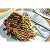 A plate of grilled meat with salad