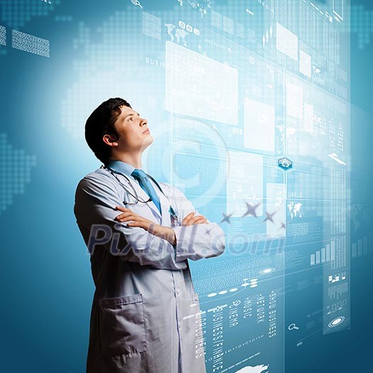 Image of young thoughtful doctor looking at media screen Image of young thoughtful doctor looking at media screen