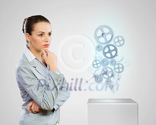 Image of thoughtful businesswoman looking at gears. Business structure Image of thoughtful businesswoman looking at gears. Business structure