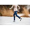 Young woman ice skating outdoors on a pond on a freezing winter day (motion blurred image)