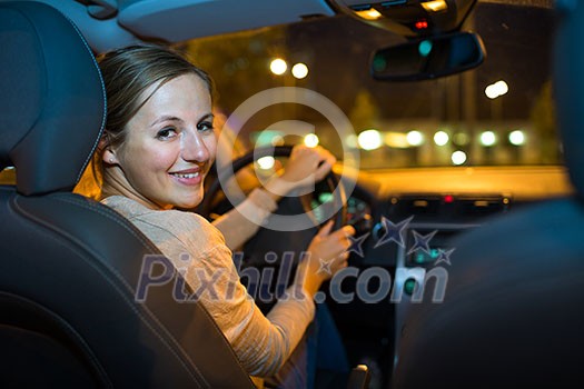 Pretty young woman driving her new car at night