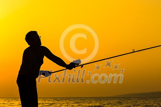 Fisherman silhouette on the beach at colorful sunset