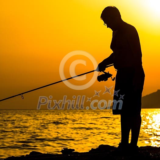 Fisherman silhouette on the beach at colorful sunset Fisherman silhouette on the beach at colorful sunset
