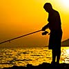 Fisherman silhouette on the beach at colorful sunset