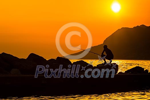 Fisherman silhouette on the beach at colorful sunset Fisherman silhouette on the beach at colorful sunset
