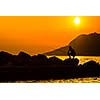 Fisherman silhouette on the beach at colorful sunset