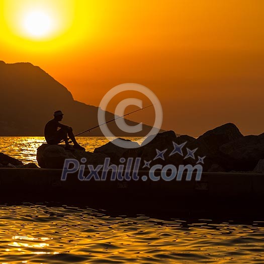 Fisherman silhouette on the beach at colorful sunset Fisherman silhouette on the beach at colorful sunset