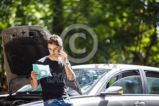 Handsome young man calling for assistance with his car broken down by the roadside